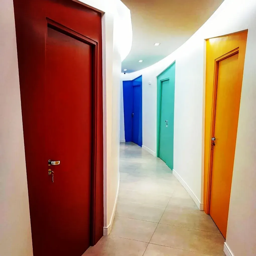 Corredor curvo com portas coloridas: vermelha, azul, verde e laranja