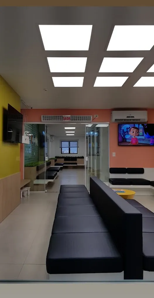 Sala de espera com paredes coloridas, bancos confortáveis e TV com desenhos